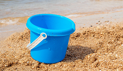 empty bucket in sand by water